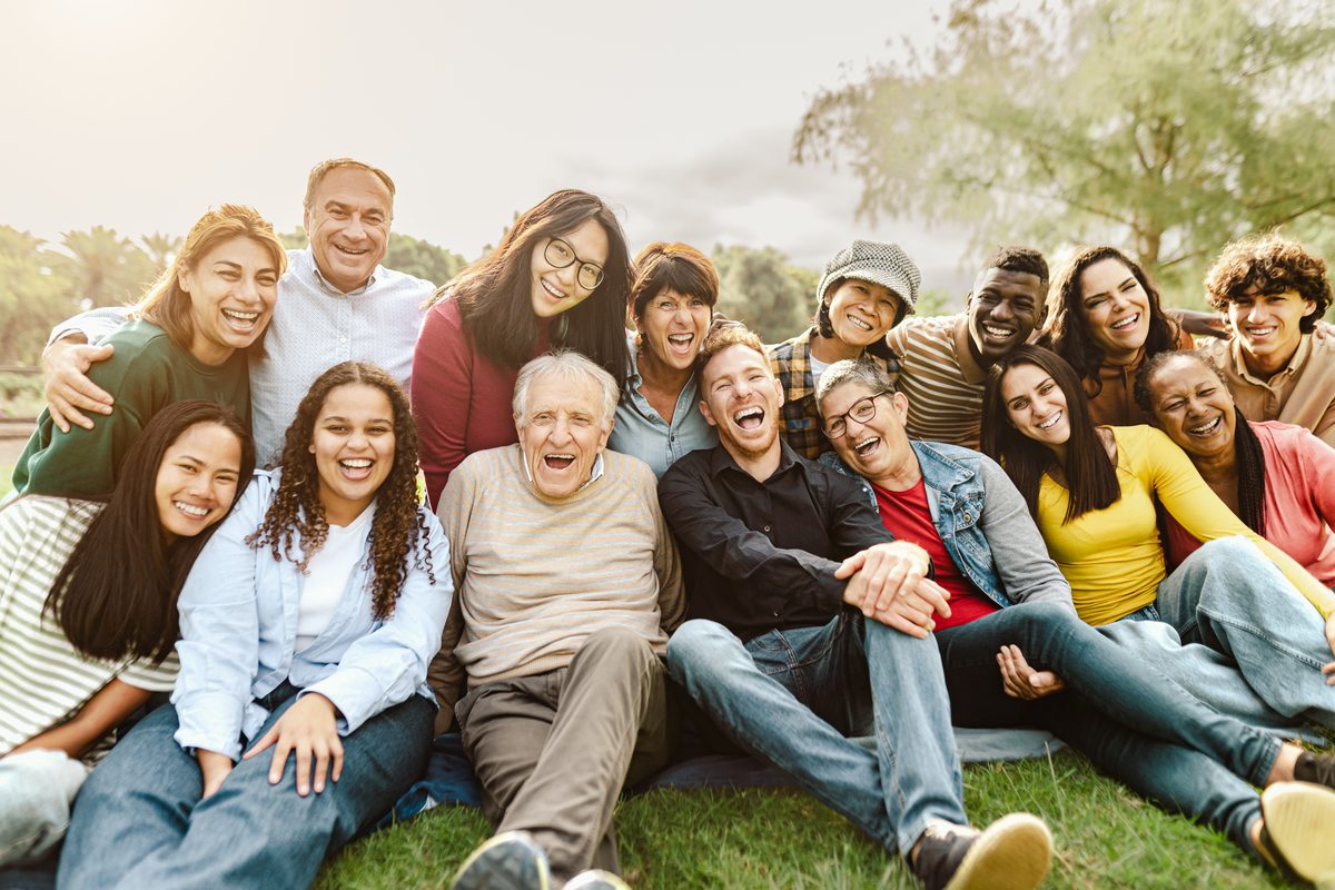 A joyful multigenerational, multiracial family laughing together in a park